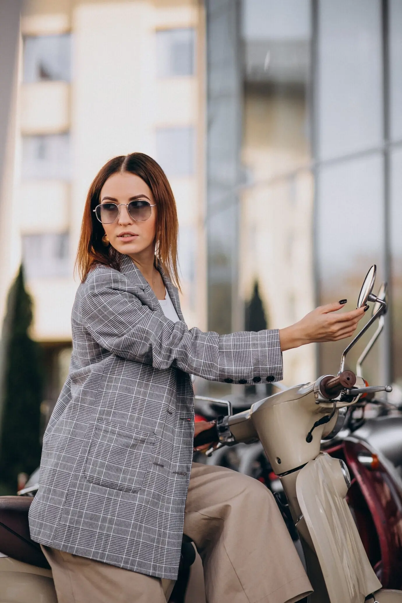 Junge Frau im Anzug steht neben dem Scooter.